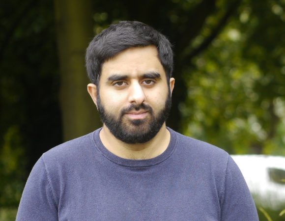 Young man standing in a field looking at camera