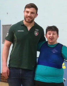 A person with learning disabilities posing with Leicester Tigers player Harry Wells