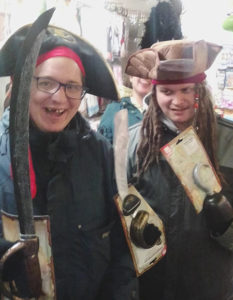 Two people with learning disabilities smiling and posing in pirate costumes