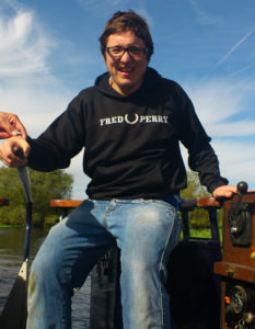 A person with learning disabilities smiling and driving a canal boat