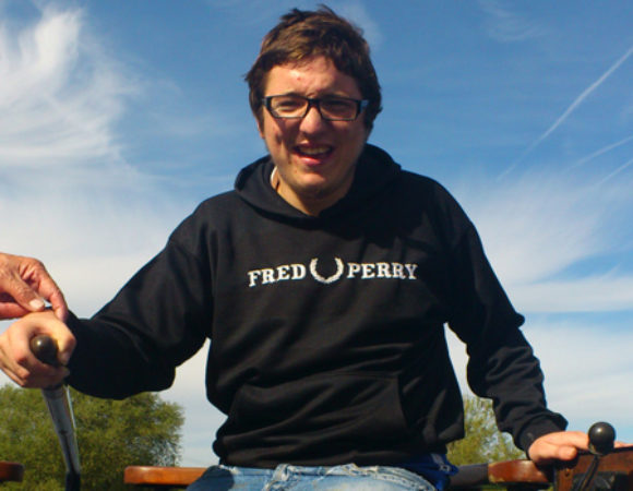 A person with learning disabilities smiling and driving a canal boat