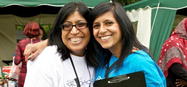 Two female volunteers standing in front of an outdoor stall